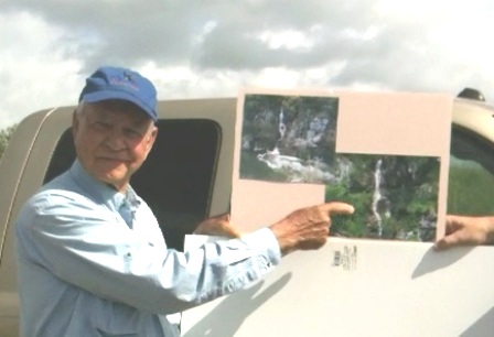 Man pointing an images of a waterfall.