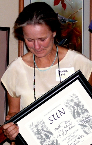 Woman holding framed image that reads "Sun" and illegible script
