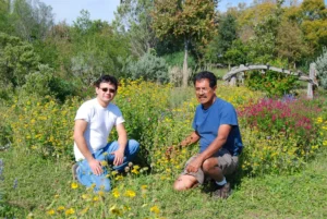 Two people sitting in front of a colorful bed of wildflowers